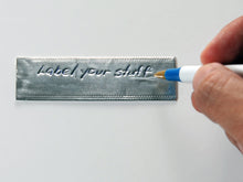 Load image into Gallery viewer, Example of writing with the Emboss-O-Tag Double Sided Write On Metal Tags with a ball point pen.  The text on the label says "Label your stuff".