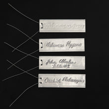 Load image into Gallery viewer, 4 examples of Emboss-O-Tags with markings on the tags made with a ball point pen and attached wires.