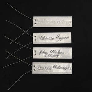 4 examples of Emboss-O-Tags with markings on the tags made with a ball point pen and attached wires.