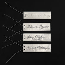Load image into Gallery viewer, 4 examples of Emboss-O-Tags with markings on the tags made with a ball point pen and attached wires.
